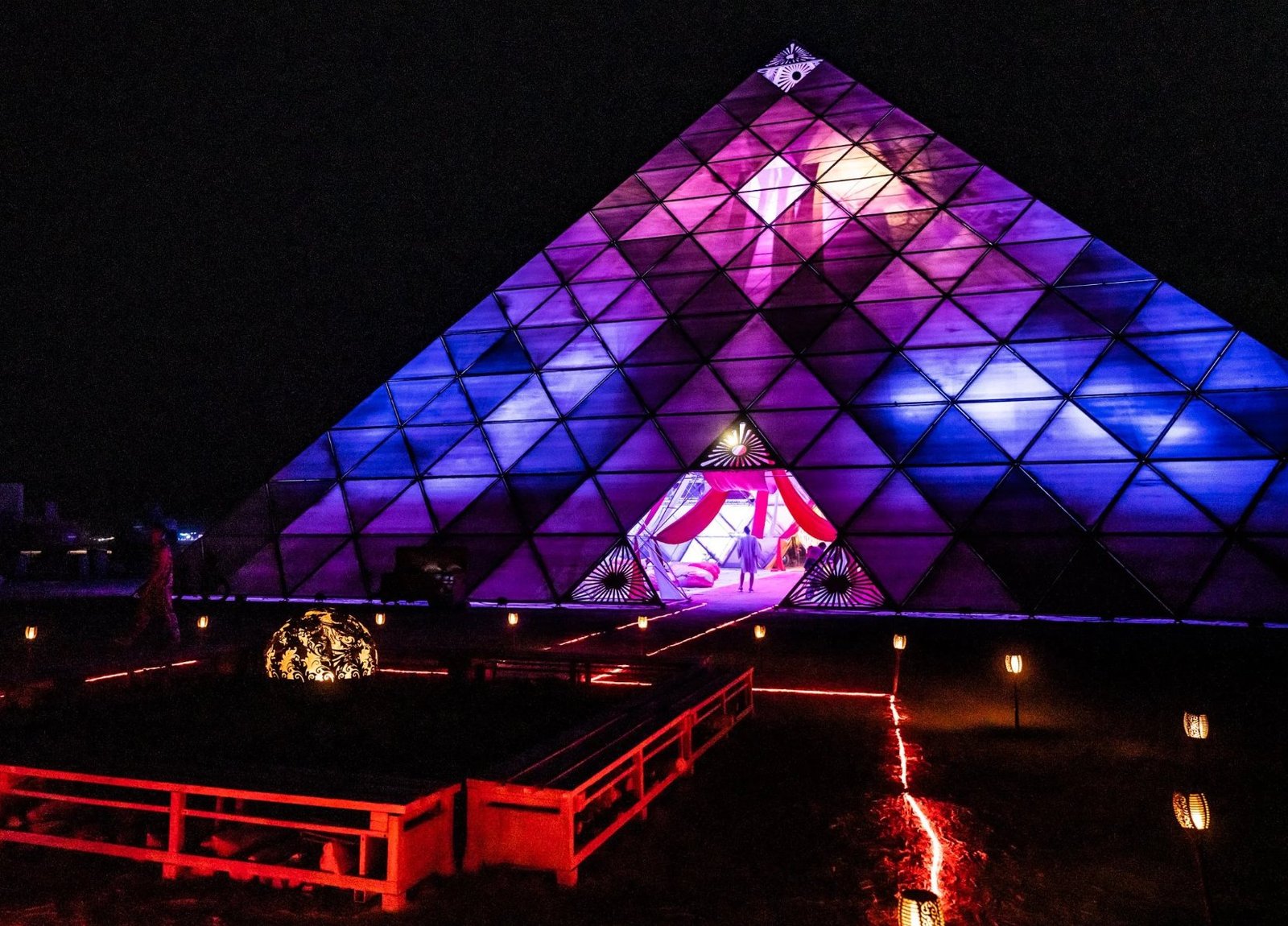 PlayAlchemist pyramid — illuminated in blue and purple at night